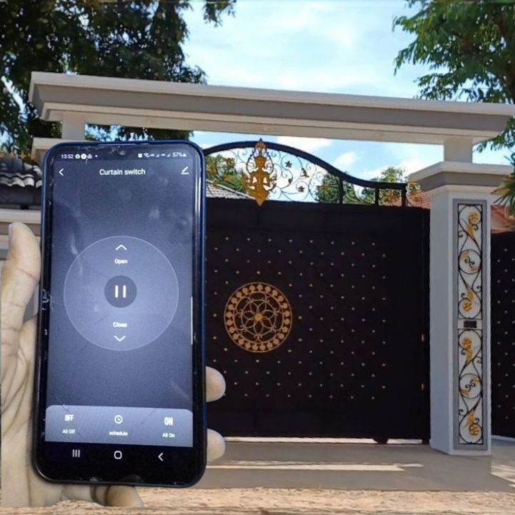 Hand holding smartphone controlling automatic sliding gate via mobile app, with ornate black and gold gate in background.